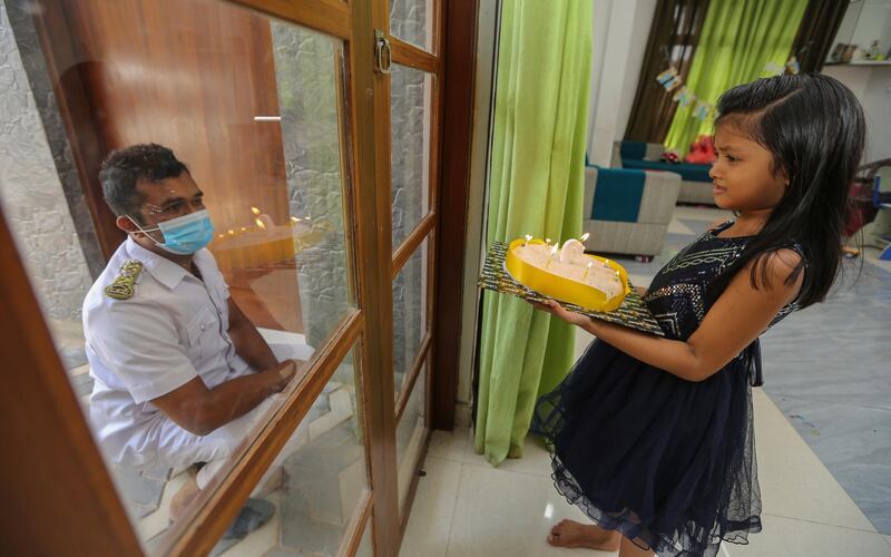Colombo Public Health Inspector Mindika Janaka Pitawela and his daughter Minadi Sahansa Pitawela, are separated by a glass panel in their home in Pannipitiya suburbs of Colombo, Sri Lanka.  EPA