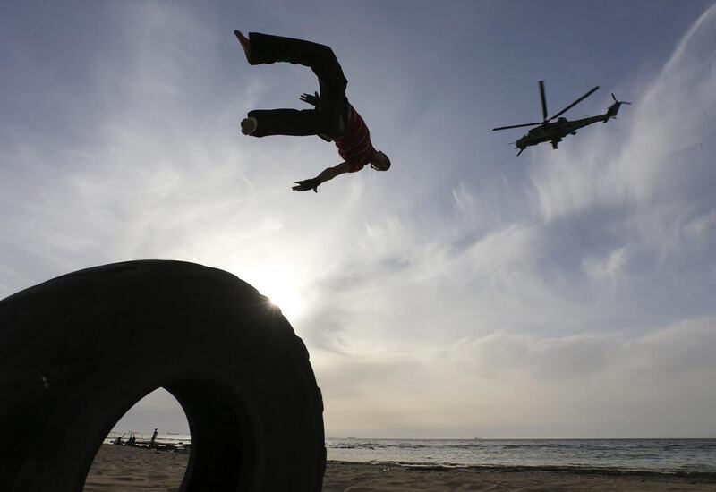 A Libyan man practices parkour, as a helicopter flies past, at a beach in Benghazi, Libya.  Esam Omran Al-Fetori / Reuters