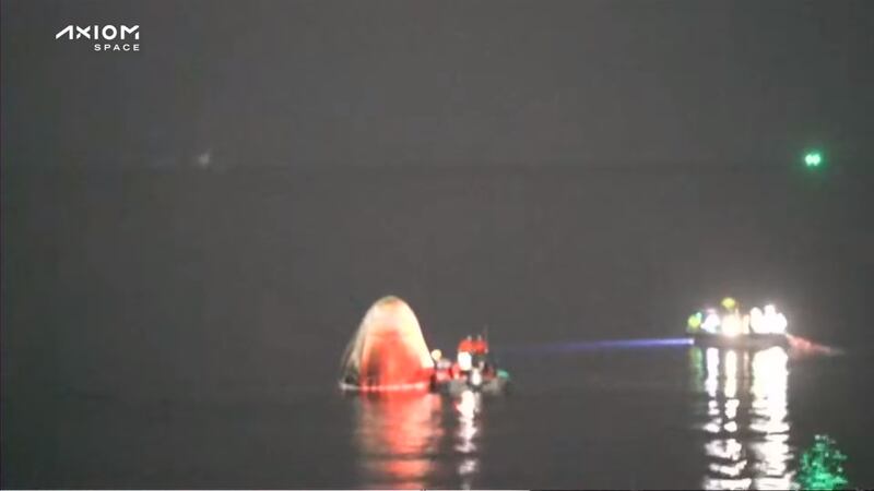 The capsule resting on top of the water with rescue boats alongside