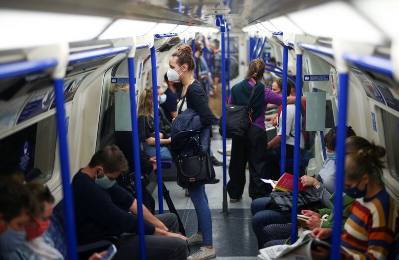 People wearing face masks ride a train on the London Underground.