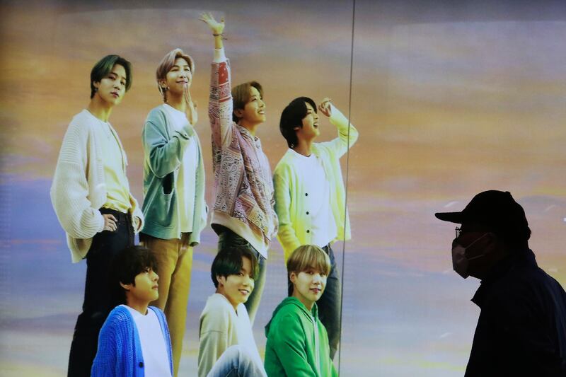 A man walks past a board showing BTS at a duty free shop in Seoul. AP Photo