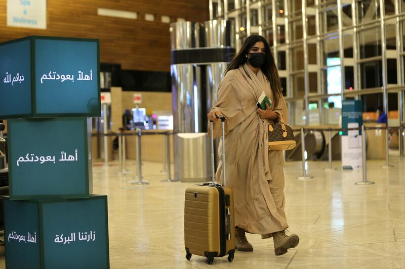 A Saudi woman wearing a facemask walks with her luggage as she arrives at the King Khalid International Airport as Saudi authorities lift the travel ban on its citizens after 14 months due to Covid-19 restrictions. Reuters