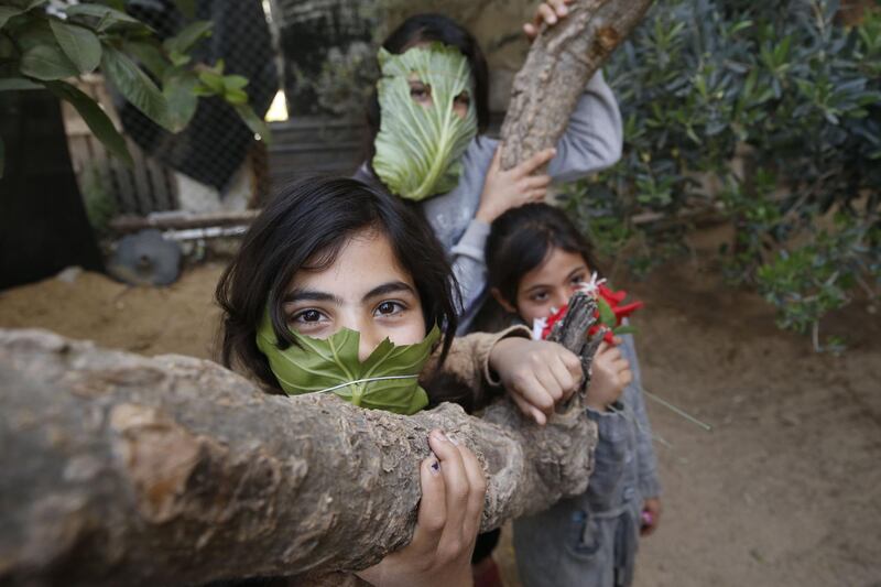 Palestinian children pose with makeshifts masks made of cabbage while cooking at home with their family in Beit Lahia in the northern Gaza Strip. AFP