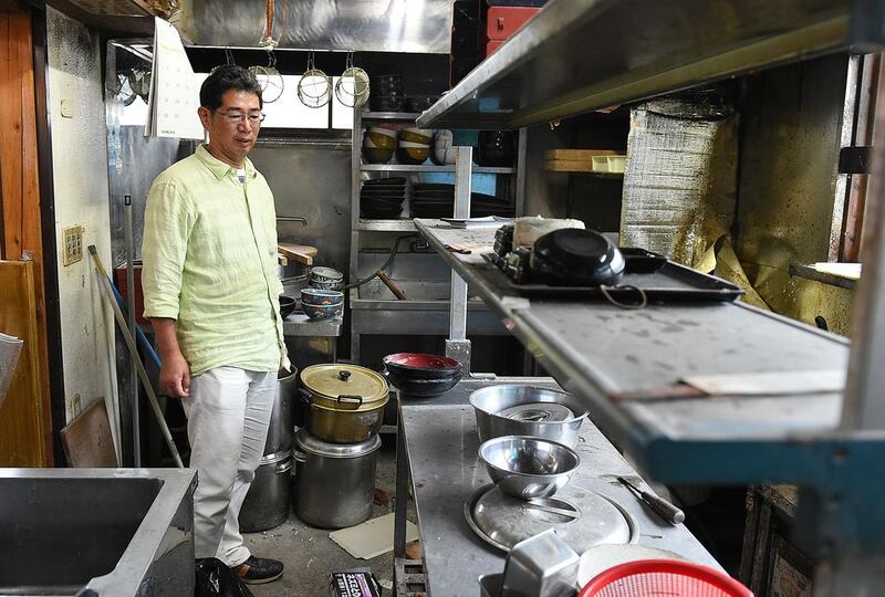 Satoru Yamauchi looking at the abandoned kitchen inside his dust-covered noodle restaurant in Naraha, a tiny town in Fukushima prefecture on July 15, 2015 – more than four years after fear of radiation spreading from the tsunami-wrecked Fukushima nuclear plant forced him to flee.  Toshifumi Kitamura/AFP Photo