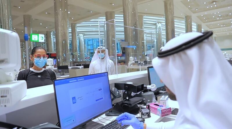 An immigration official checks documents of passenger at Dubai Airport. WAM