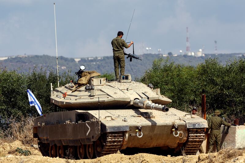 An Israeli soldier adjusts his rifle as he stands on a tank near Israel's border with Lebanon in northern Israel. Reuters