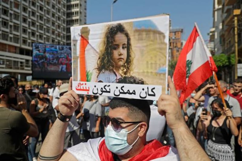 A demonstrator marches with a sign showing one of the young victims of the 2020 Beirut blast.