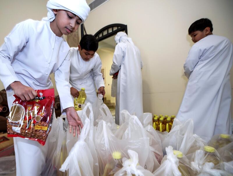 Abu Dhabi, United Arab Emirates, April 30, 2020.   
 Filipino woman, Mona Mohamed Baraguir who donates rice, eggs, cooking oil and other daily essentials to laid off workers.
Mona with her children, (L-R) Fares-9, Hamed Khalifa-15,  Ali-13 and Saed- 11. 
The boys help pack the daily supplies.
Victor Besa / The National
Section:  NA
Reporter:  Shireena Al Nuwais