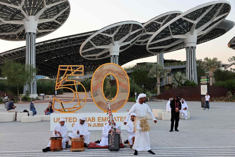 A traditional group performs in front of a sign celebrating the UAE's 50th anniversary. AFP
