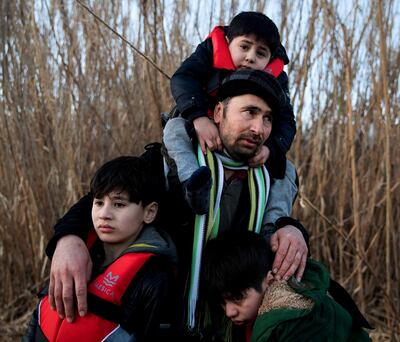 A man holds his three sons as migrants from Afghanistan arrive on a dinghy on a beach near the village of Skala Sikamias, after crossing part of the Aegean Sea from Turkey to the island of Lesbos, Greece, March 2, 2020. REUTERS/Alkis Konstantinidis/File Photo     TPX IMAGES OF THE DAY      SEARCH "GLOBAL POY" FOR THIS STORY. SEARCH "REUTERS POY" FOR ALL BEST OF 2020 PACKAGES.