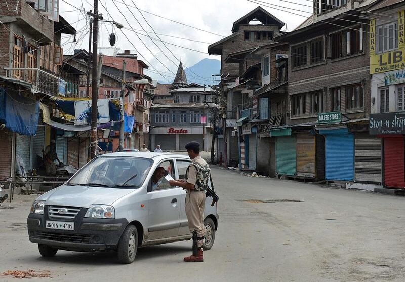 An Indian paramilitary trooper checks a car driver's papers during heightened security and a general strike in Srinagar as the prime minister, Narendra Modi, visited Kashmir state on July 4, 2014. Tauseef Mustafa / AFP

