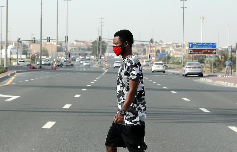 DUBAI, UNITED ARAB EMIRATES , April 18– 2020 :- A pedestrian wearing a face mask crosses the street in International City in Dubai. Only two entrance are open for vehicles coming from Al Awir road before the Dragon Mart 1 and Manama Street to International City in Dubai.  Dubai is conducting 24 hours sterilisation programme across all areas and communities in the Emirate and told residents to stay at home. UAE government told residents to wear face mask and gloves all the times outside the home whether they are showing symptoms of Covid-19 or not.  (Pawan Singh / The National) For News/Online