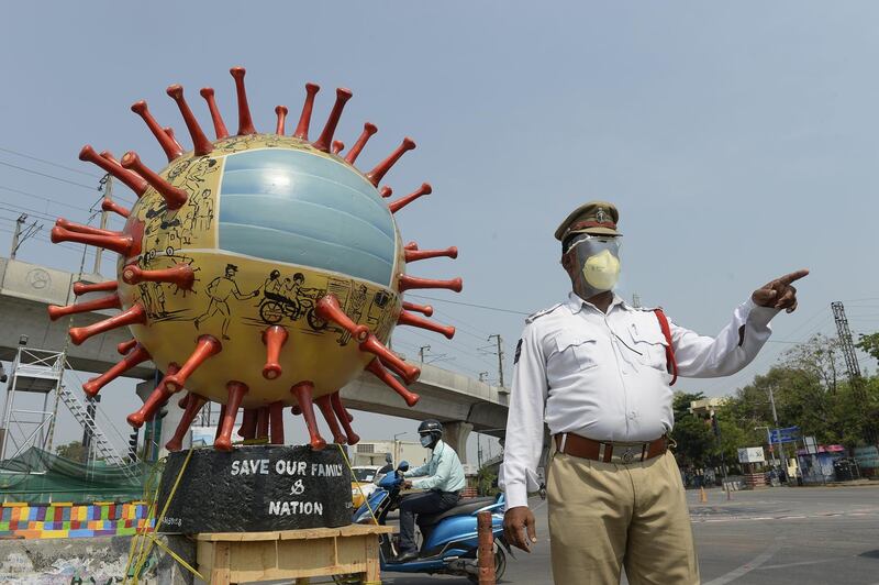 An Indian traffic officer stands beside a coronavirus-themed globe at a traffic junction as he checks commuters travelling during a government-imposed nationwide lockdown in Hyderabad. AFP