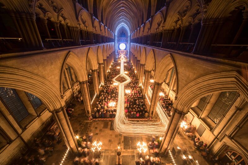 The UK's Salisbury Cathedral is illuminated by trails of candles carried by choristers during the annual 'darkness to light' advent procession. Getty Images