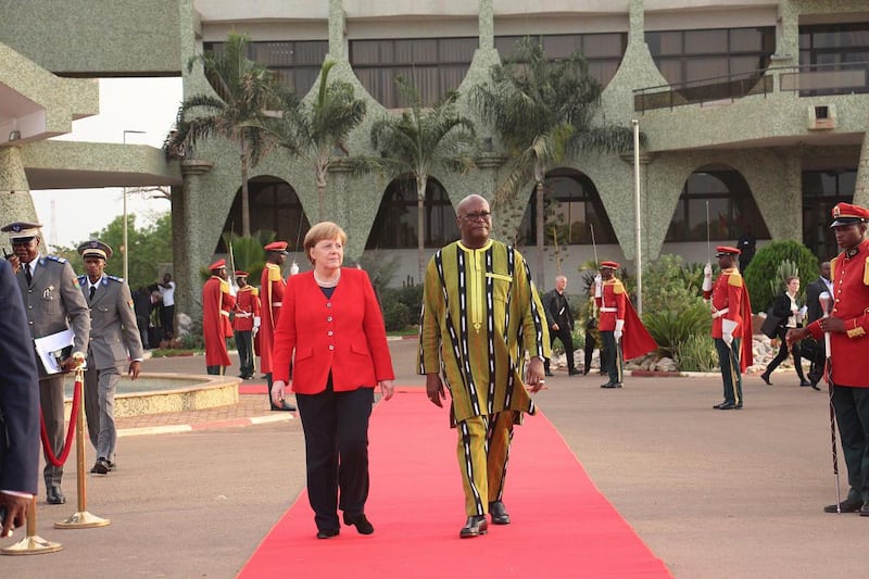 German Chancellor Angela Merkel, center left, is welcomed by Burkina Faso President, Roch Marc Christian Kabore, right, at the Presidential Palace in Ouagadougou, Burkina Faso, Wednesday, May 1, 2019. Merkel has arrived in the West African nation of Burkina Faso. Merkel is on a three-nation tour in the region. (AP Photo/Alain Didier Compaore)