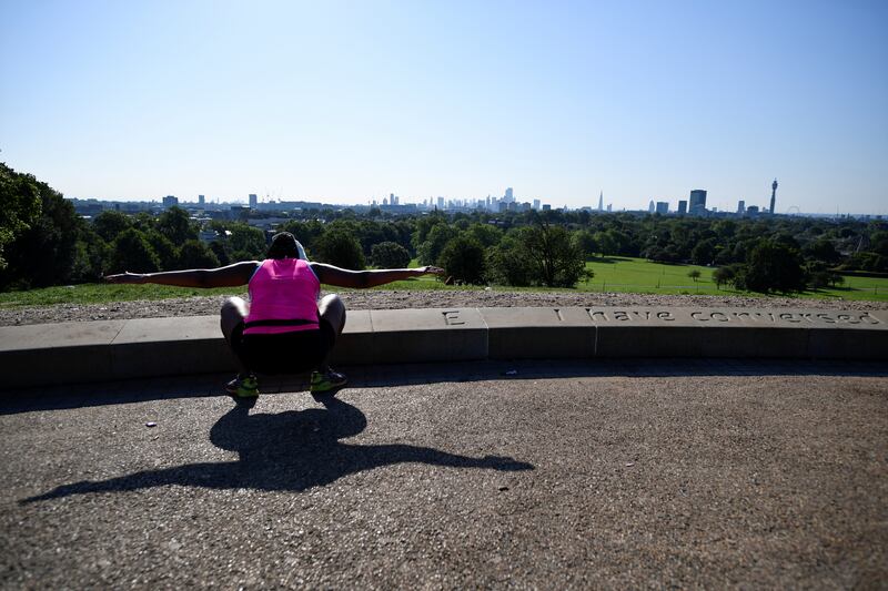 A person enjoys their morning exercise during sunny weather on Primrose Hill in London.