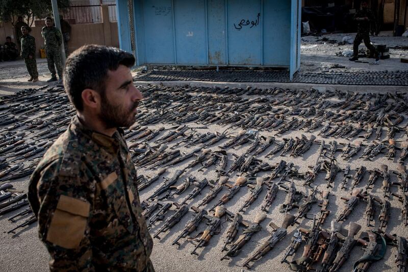 An SDF (Syrian Democratic Forces) fighter looks over seized ISIS weapons that were found in the last stronghold of the extremist group as they were displayed.  Getty