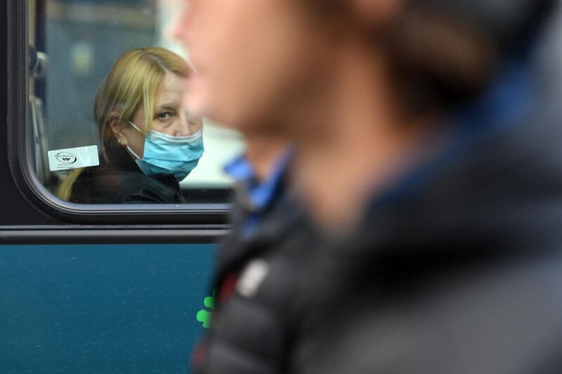 A woman wearing a protective face covering looks from the window of a bus at protesters march during the anti-vax rally in Liverpool. AFP