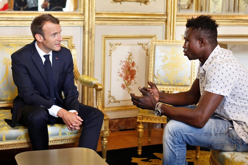 TOPSHOT - French President Emmanuel Macron (L) speaks with Mamoudou Gassama, 22, from Mali, at the presidential Elysee Palace in Paris, on May, 28, 2018.  Mamoudou Gassama living illegally in France is being honored by Macron for scaling an apartment building over the weekend to save a 4-year-old child dangling from a fifth-floor balcony. / AFP / POOL / Thibault Camus
