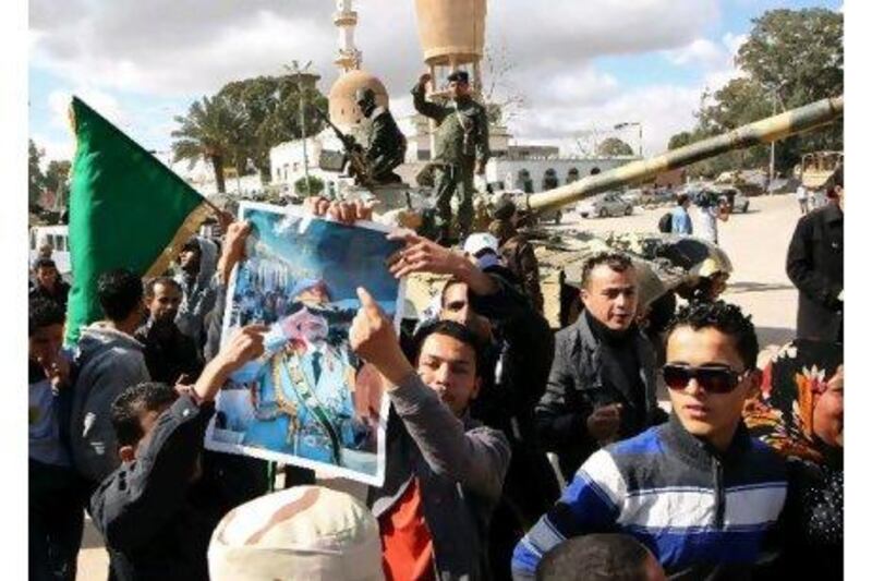 Supporters of Muammar Qaddafi brandish his portrait in Qasr bin Ghashir, south of Tripoli, yesterday as Libya's tumult continues.