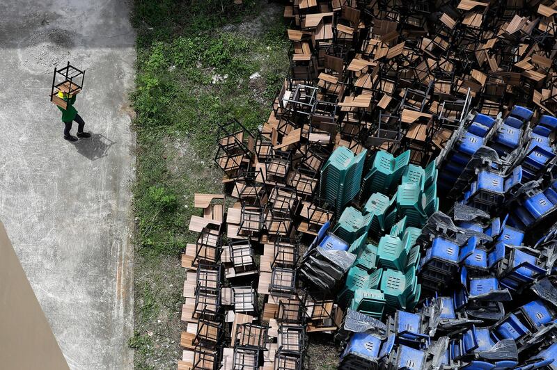 A worker arranges chairs as they temporarily convert a public school to a Covid-19 quarantine facility in Quezon city, Philippines. AP Photo