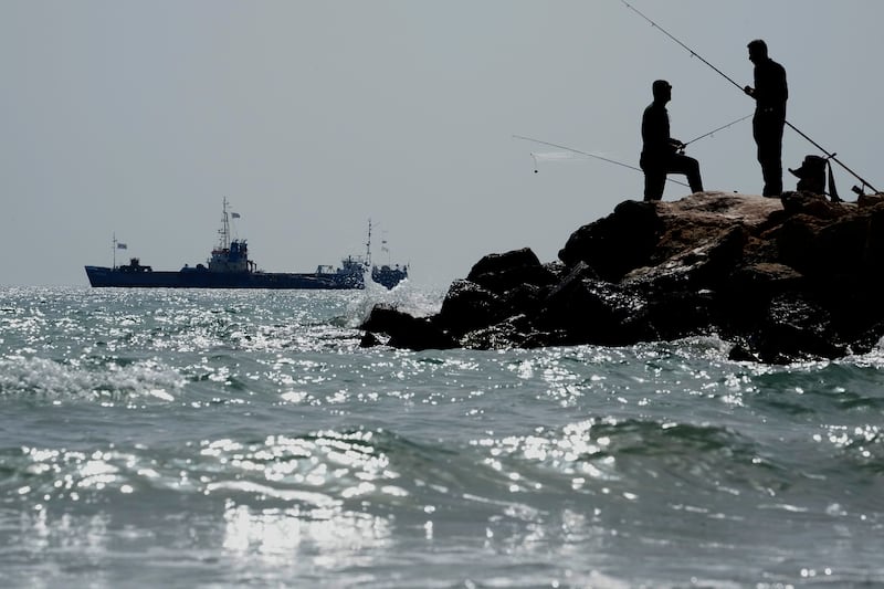 The Jennifer, a ship loaded with canned food, prepares to set sail for Gaza as men fish from the rocks near the port of Larnaca in Cyprus. AP