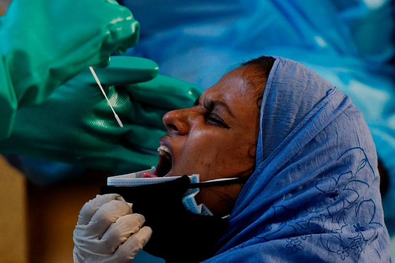 Medical staff collect a sample from an Indian citizen flown home from Dubai by Air India flight at the Chennai International Airport in southern Tamil Nadu state. AFP