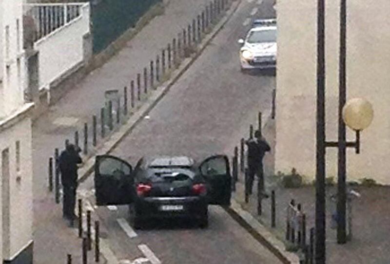 Armed gunmen face police officers near the offices of the French satirical newspaper Charlie Hebdo in Paris on January 7, 2015. AFP 