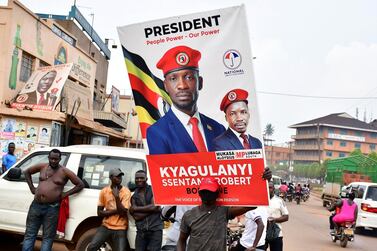 A supporter of Ugandan opposition presidential candidate Robert Kyagulanyi Ssentamu, also known as Bobi Wine, carry a campaign poster ahead of the presidential and parliamentary elections, in Kampala, January 12, 2021. Reuters 