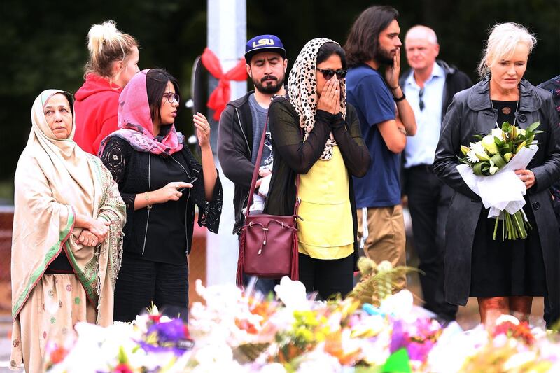 People react as they look at the floral tributes laid near Al Noor mosque. AFP