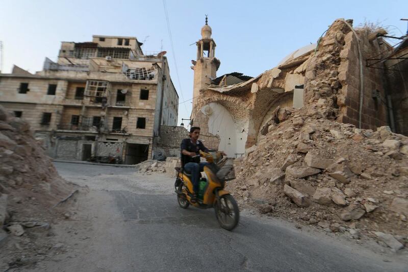 A man drives a motorcycle near damaged buildings in Old Aleppo's Kadi Askar area (REUTERS/Abdalrhman Ismail)