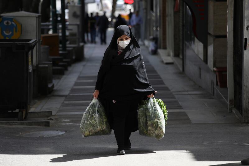 A woman wearing a face mask to protect against the new coronavirus carries her shopping in northern Tehran, Iran, Saturday, April 4, 2020. In the first working day after Iranian New Year holidays authorities have allowed some government offices and businesses to re-open with limited working hours, when schools, universities, and many businesses still are ordered to be closed aimed to prevent the spread of the virus.  (AP Photo/Vahid Salemi)