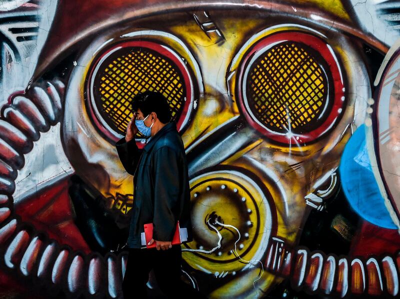 A man walks by a graffiti in Bogota. Colombia will begin a new phase against the pandemic in September with "specific restrictions" and reactivation of economic sectors given the downward trend in infections, President Ivan Duque announced.  AFP