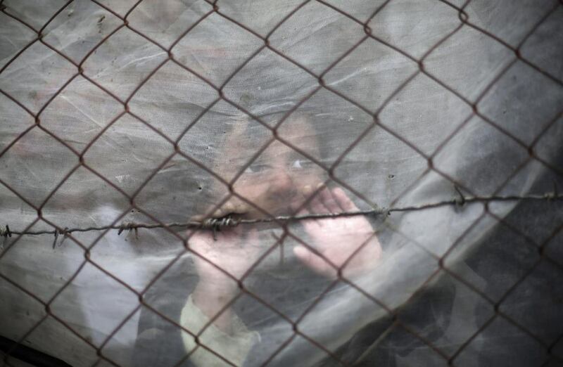 A Palestinian girl peers out  on December 28, 2016, from behind cloth surrounding her family's house during a rainy, cold day in a slum on the outskirts of Khan Younis refugee camp, Gaza Strip. Khalil Hamra / Associated Press