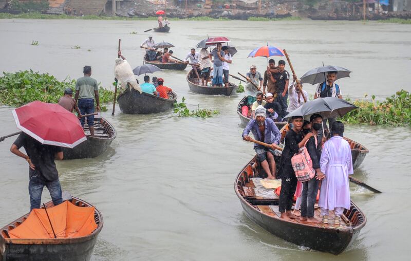 People hold umbrellas as they cross the Buriganga River on boats during a rainy day in Dhaka, Bangladesh. EPA