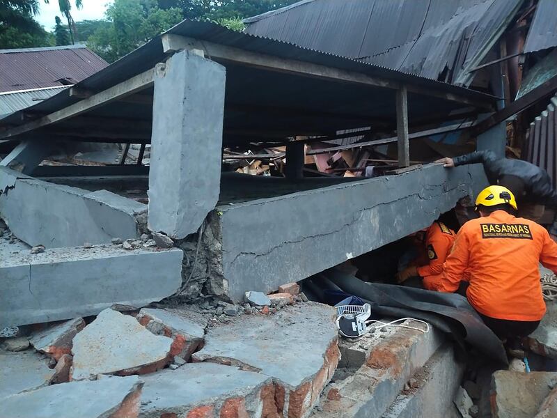 Rescuers look for survivors trapped in a collapsed building in Mamuju. National Search and Rescue Agency (BASARNAS) / AFP