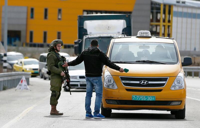 An Israeli soldier checks the documents of a Palestinian taxi passenger on their way out of the West Bank village of Ein Sinya, in northern Ramallah on February 1, 2016 as Israel blocked non-residents from Ramallah in response to a checkpoint shooting that wounded three soldiers a day earlier. Abbas Momani/AFP
