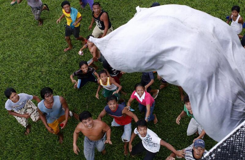 Survivors of Super Typhoon Haiyan wait for a sack containing food supplies to drop from a Philippine Air Force helicopter in Tolosa, Leyte in central Philippines November 21, 2013. Typhoon Haiyan, which hit Philippines on November 8, killed more than 4,000 people and left another 4 million homeless.    REUTERS/Erik De Castro (PHILIPPINES - Tags: DISASTER ENVIRONMENT FOOD TRANSPORT)
