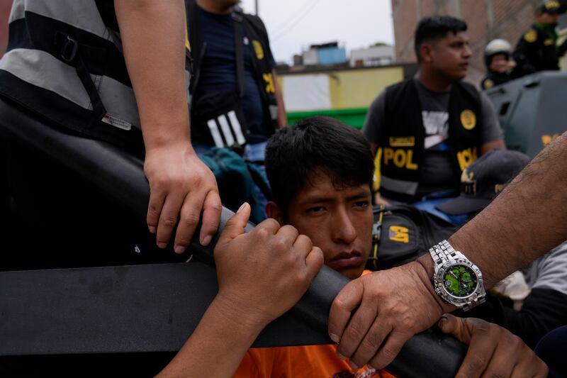 A detained anti-government protester sits in the back of a police vehicle at the San Marcos University in Lima. AP