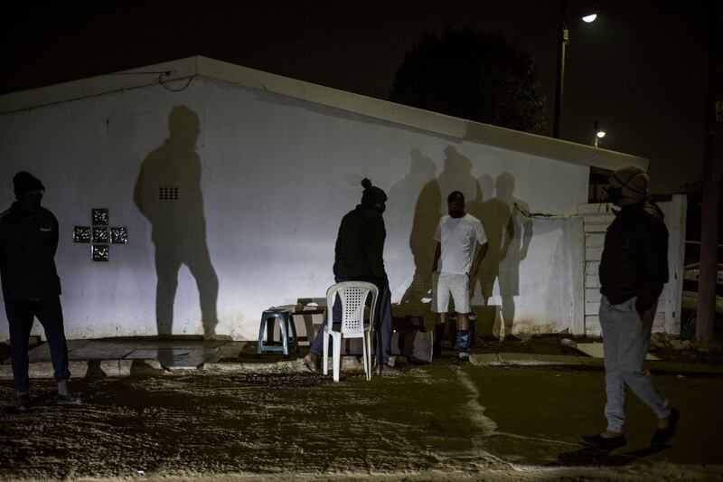 Shadows of men, members of the Phoenix Community Policing Forum, a grassroots mobilisation group involving local residents, are cast on the outside wall of a house while he and other members are on a lookout in Durban, on July 20, 2021.  - Phoenix is flashpoint town between black South Africans and counterparts of Indian origin where at least 20 people died in the recent wave of violence.  Like communities across South Africa, residents of the predominantly ethnic Indian town set up their own protection squads in response to pillaging and arson that broke out days after the jailing of ex-president Jacob Zuma on July 8th -- overwhelming security forces.