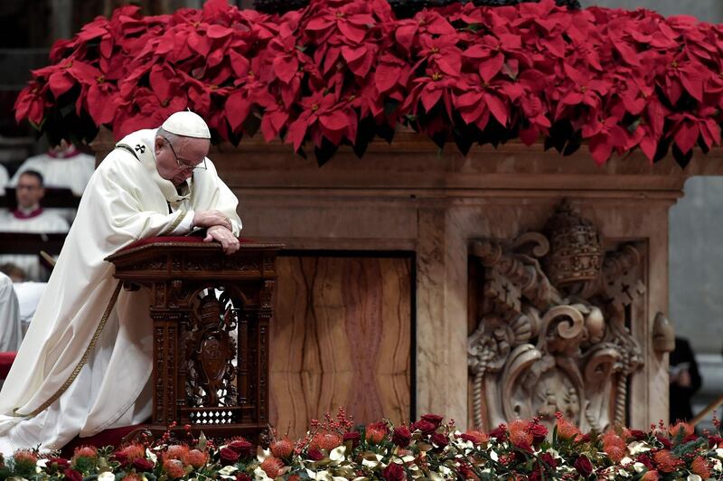 Pope Francis kneels down to pray as he celebrates mass on Christmas Eve, marking the birth of Jesus Christ at St Peter's basilica in Vatican. AFP