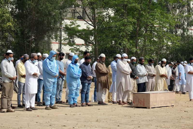 People pray while attending a funeral service for a Covid-19 fatality at a burial ground in New Delhi, India. Bloomberg