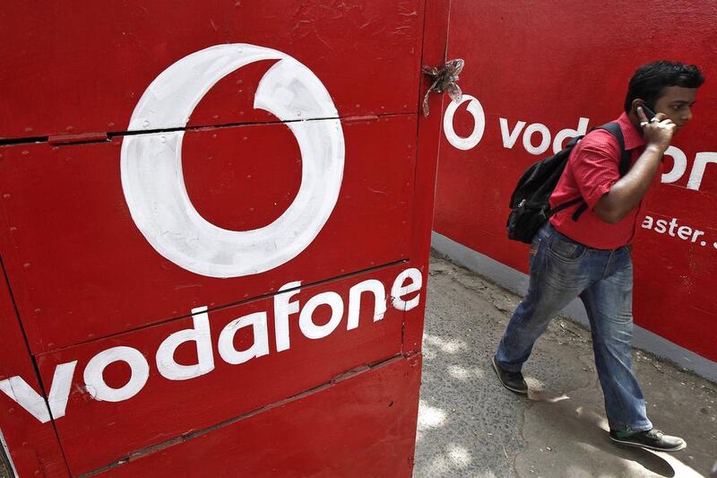 A man speaks on his mobile phone as he walks past logos of Vodafone painted on a roadside wall in Kolkata. Rupak De Chowdhuri / Reuters