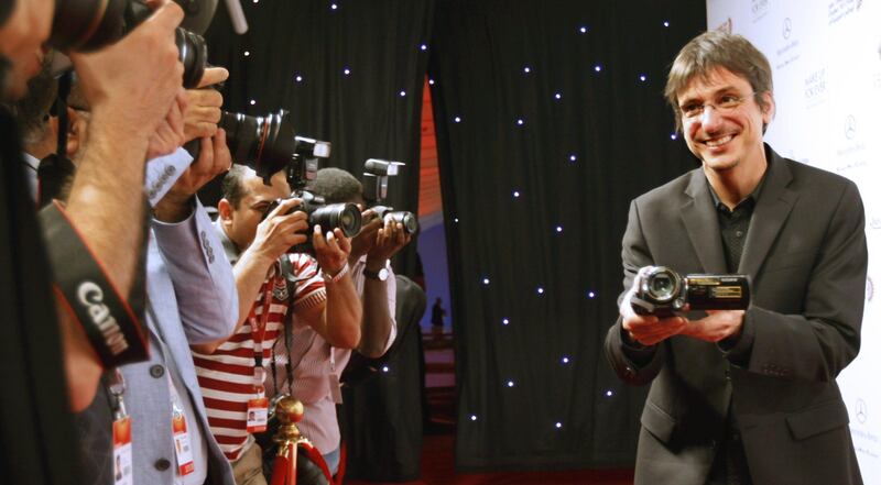 Canadian Film director Philippe Falardeau aims his video camera to the photographers as he walks on the red carpet at the opening ceremony of the fifth Abu Dhabi Film Festival in the United Arab Emirates' capital on October 13, 2011.  AFP PHOTO/JOSEPH CAPELLAN
 *** Local Caption ***  045235-01-08.jpg