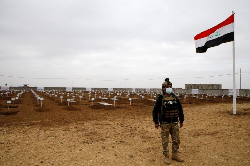 A member of the security forces stands guard in front of the graves dug for victims of ISIS in Kocho village in northern Iraq. Reuters