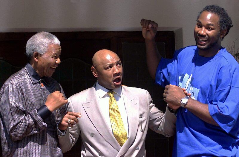 Former South African president Nelson Mandela (L) strikes a fighting pose with former world middleweight champion Marvin Hagler (C) and former world heavyweight boxing champion Lennox Lewis April 23,2001. Reuters
