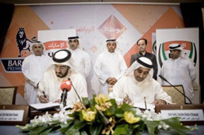 Mohamed Najeeb, front left, the head of Abu Dhabi Al Riyadiya Channels, signs a deal with Yousuf Abdullah, the general secretary of the UAE Football Association.  Looking on are Mohamed Khalaf al Mazrouei (rear, centre), the chairman of ADMC, and Karim Sarkis (rear, second from right), the executive director of broadcast at ADMC.