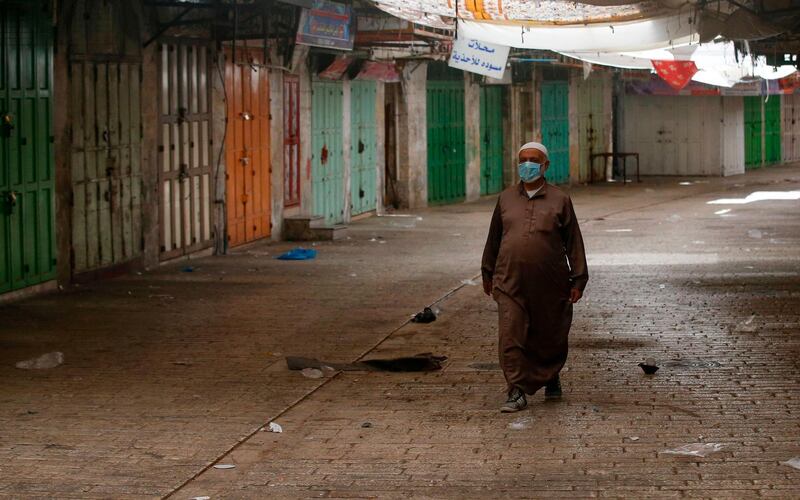 A Palestinian man walks in front of closed shops in the centre of the West Bank town of Hebron, after a surge in coronavirus cases. AFP