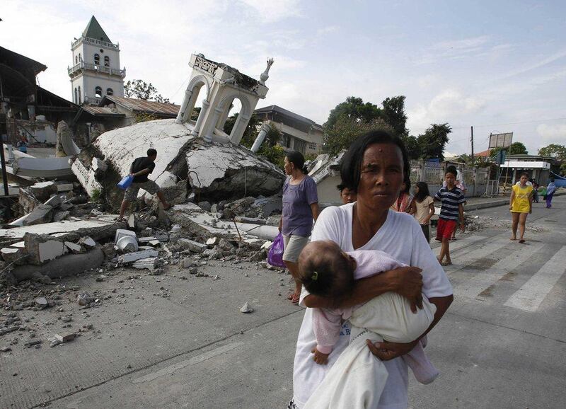 A woman carries her baby past a destroyed church in Tubigon, Bohol, a day after an earthquake hit central Philippines. Erik de Castro / Reuters