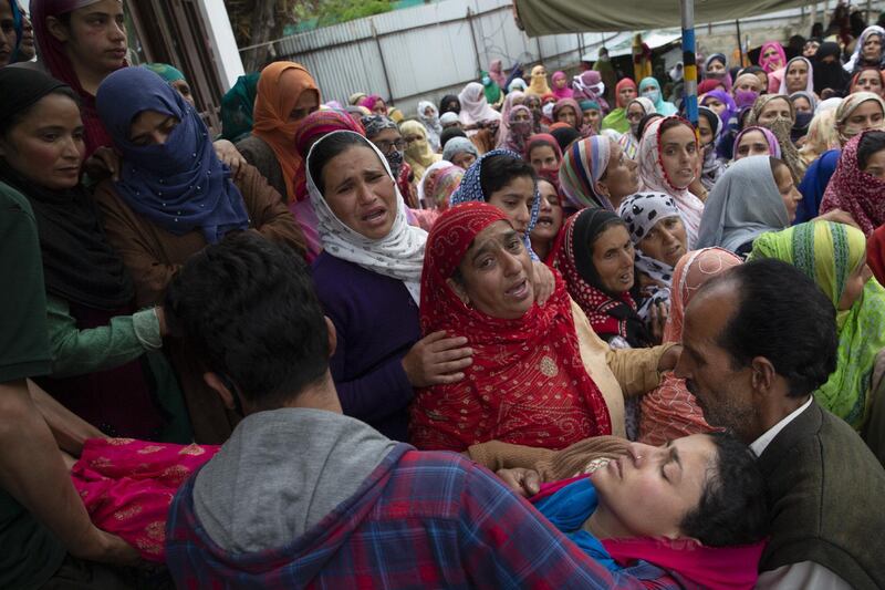 Kashmiri men carry a woman who fainted as she was mourning in Makhama village. AP